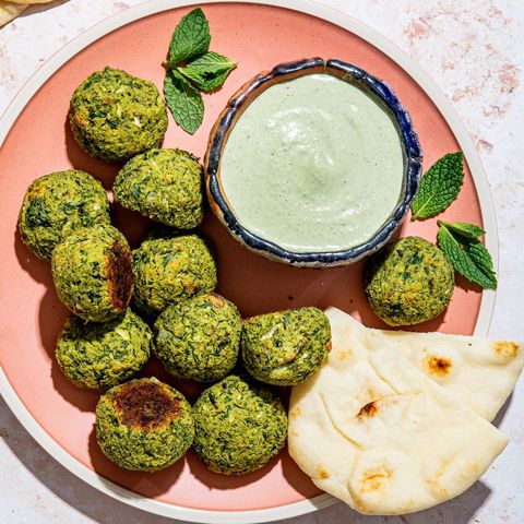 green baked falafel with mint tahini sauce and pita on a pink plate green baked falafel with mint tahini sauce and pita on a pink plate