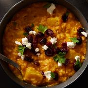 baked pumpkin risotto in a black bowl topped with cheese and dried cranberries