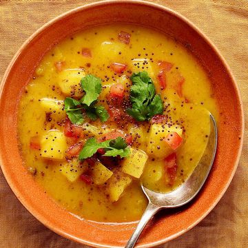 overhead shot of two bowls of potato soup with some naan bread