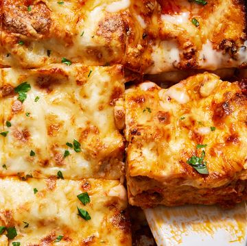 classic lasagna in a white pan topped with fresh herbs