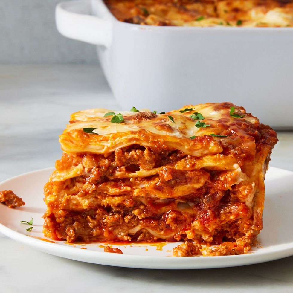 classic lasagna in a white pan topped with fresh herbs