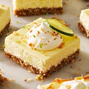 coconut key lime cheesecake bars with whipped cream, shredded toasted coconut, and lime