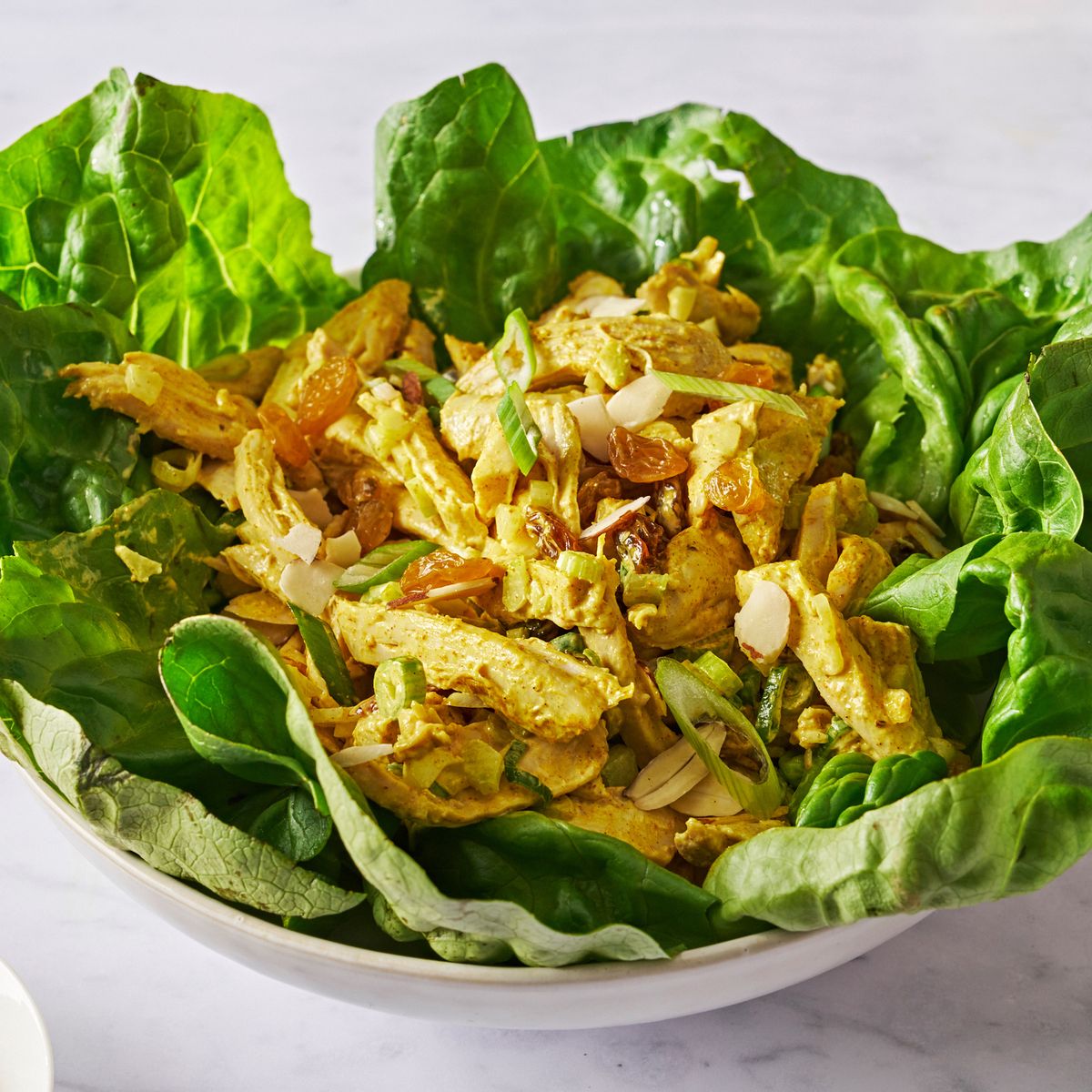 coronation chicken salad in lettuce cups with golden raisins and scallions