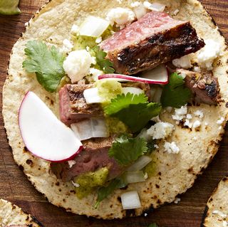 marinated, grilled skirt steak, piled into a corn tortilla with salsa verde, cilantro, red onion, cotija, and radish