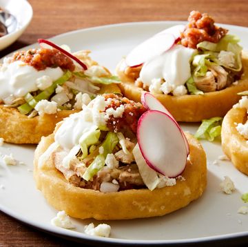 sopes made of masa harina and topped with refried beans salsa roja shredded lettuce mexican crema radishes and cojita