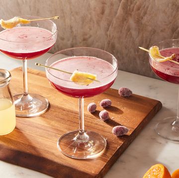 pink ginger cranberry whiskey sours in coupe glasses garnished with candied ginger