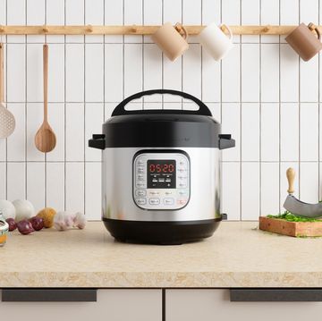 multi cooker on kitchen counter with onions, garlic, cooking oil and cutting board