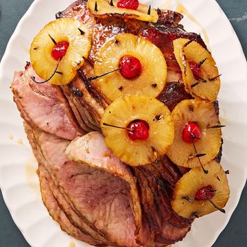 brown sugar glazed ham with pineapple rings stuck through with maraschino cherries on a white plate