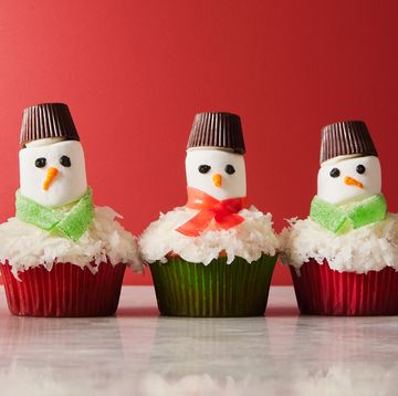 snowman cupcakes topped with shredded coconut snow, marshmallow faces, candy scarves, and peanut butter cup hats