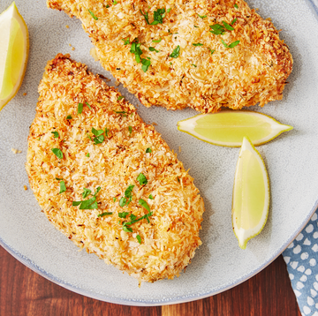 crispy breaded chicken breasts with some parsley and a few lemon wedges