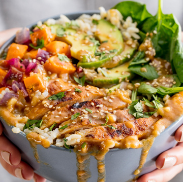 a buddha bowl full of fresh veg, spinach, avocados and saucy chicken